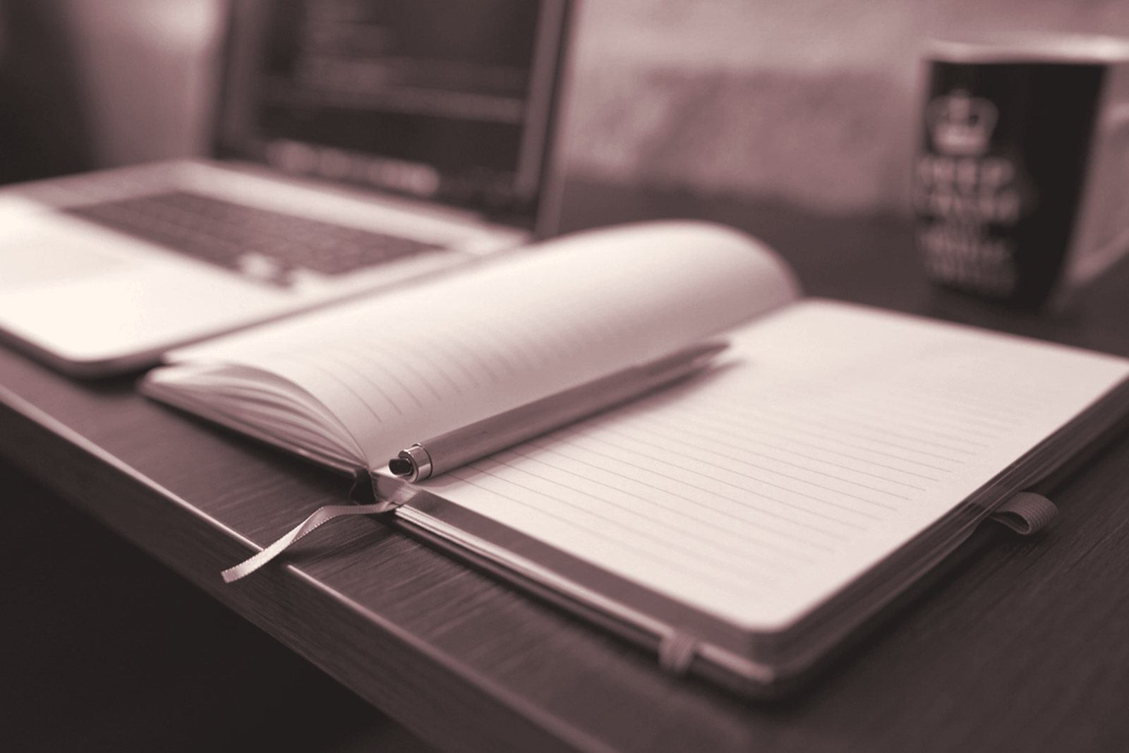An open notebook and a laptop on a desk